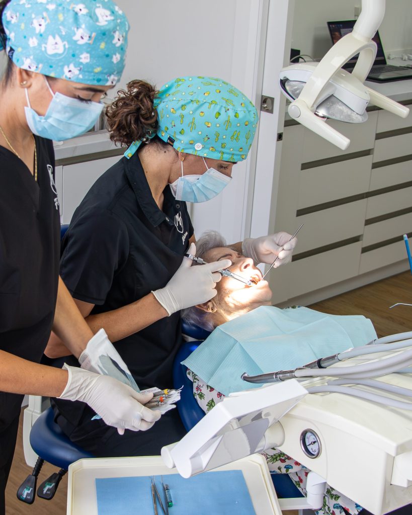 Odontóloga y auxiliar atendiendo a una paciente mayor en el gabinete dental